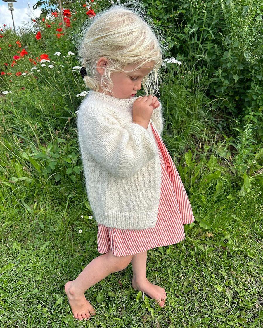 Barn iført hvid Novice Cardigan Mini – Chunky Edition