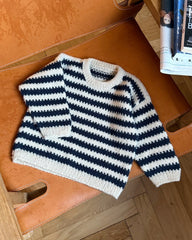 Blå og hvid Otto Sweater Junior liggende på stol