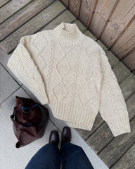 Hvid Saga Sweater liggende på bænk