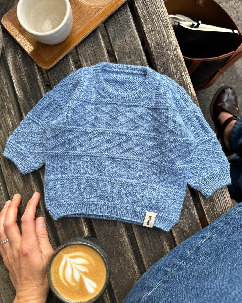 Lyseblå Storm Sweater Baby liggende på bænk