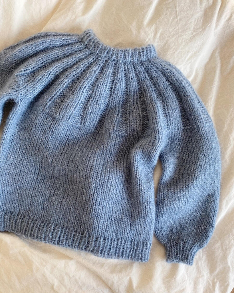 Lyseblå Sunday Sweater Junior på dyne