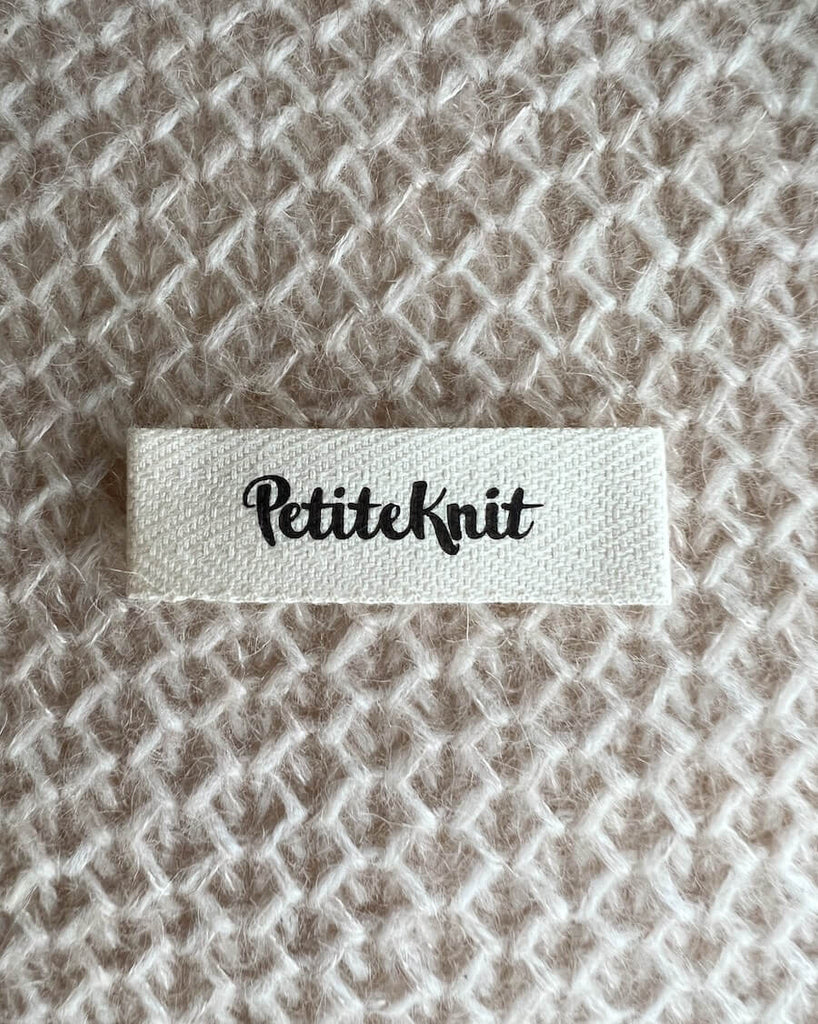 énkelt Petiteknit label med sort tekst