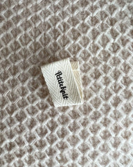 Nærbillede af "foldet "Petiteknit" label