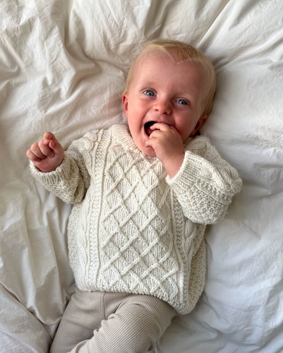Barn iført hvid Moby Sweater Baby