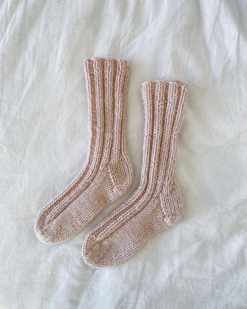 Lyserøde Sunday Socks Junior på dyne