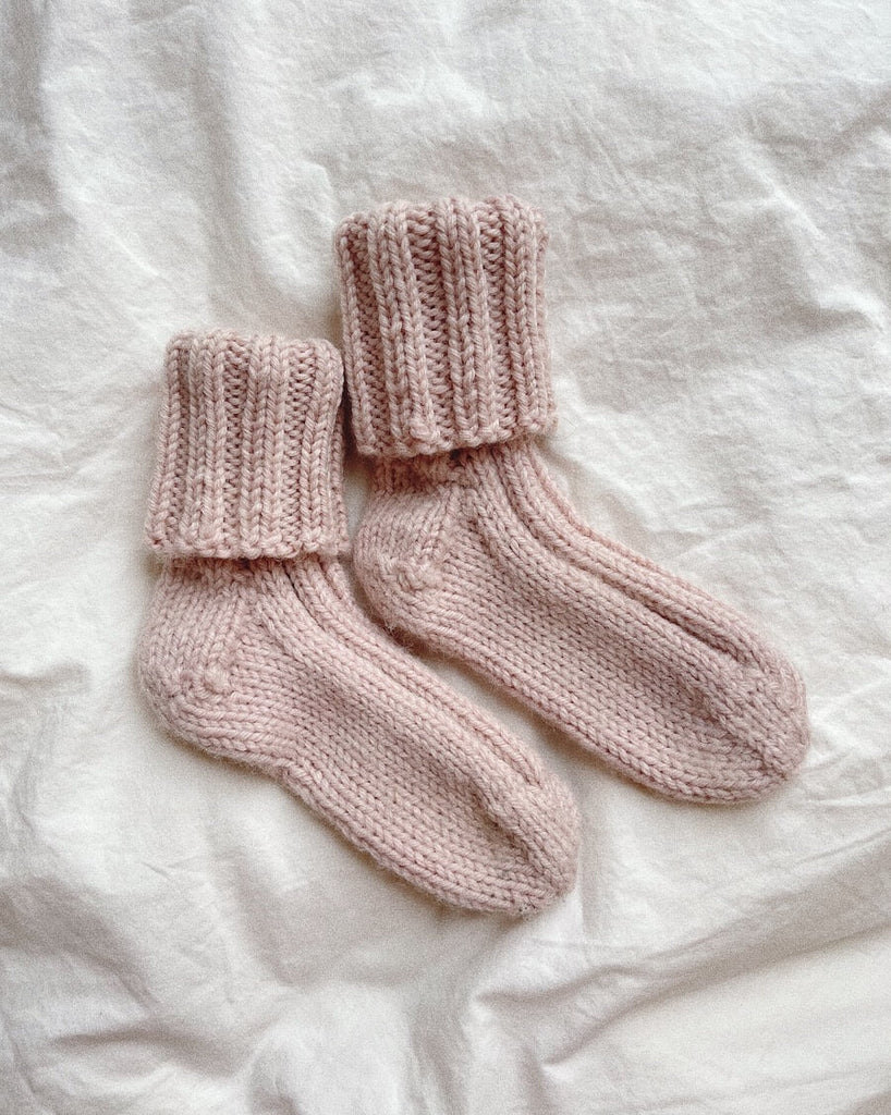 Lyserøde Sunday Socks Junior på dyne
